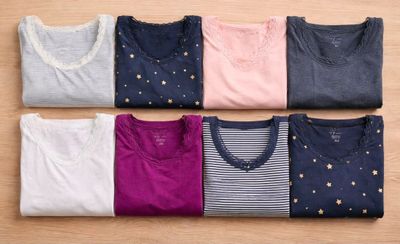six paires de t-shirts disposées en rangée sur une surface en bois