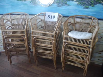 trois chaises en osier sont alignées contre un mur, avec un tableau en arrière-plan