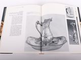 an open book with a picture of a silver pitcher on it