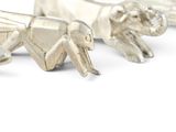 three silver figurines of elephants on a white surface