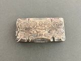 an antique silver money clip with a floral design on it