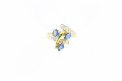 gros plan d'une bague en or avec des pierres bleues et blanches