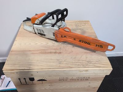 an orange and black chainsaw sitting on top of a wooden box