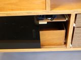 a wooden desk with a black drawer and a phone on it
