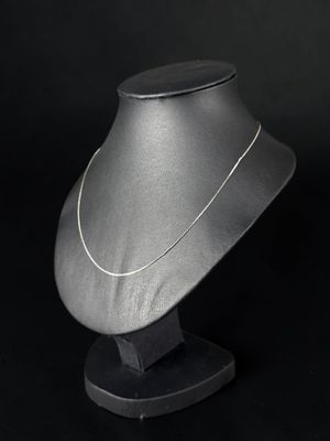 une photo en noir et blanc d'un collier en argent porté par un mannequin