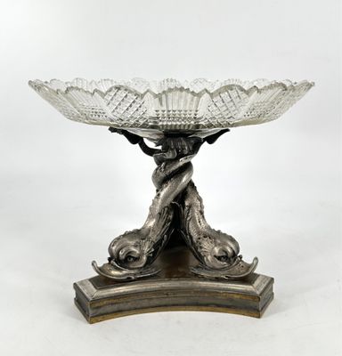 un plat ancien en argent orné d'un oiseau, posé sur un socle