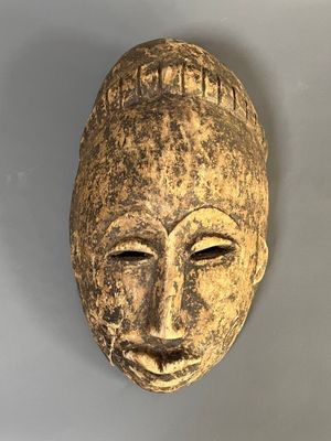 un gros plan d'un masque en bois accroché au mur