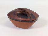 a small brown bowl with a lid on a white surface