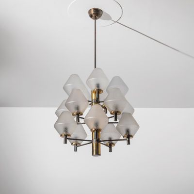 un grand lustre en laiton, dont les abat-jours en verre dépoli sont suspendus au plafond