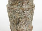 un petit vase posé sur une surface blanche