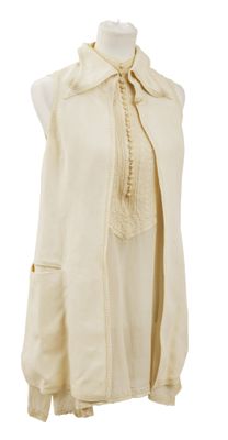 chemisier sans manches couleur crème, à volants et avec un nœud au cou, sur un mannequin de couture