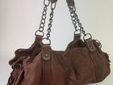 someone is holding a brown purse with a chain hanging from it