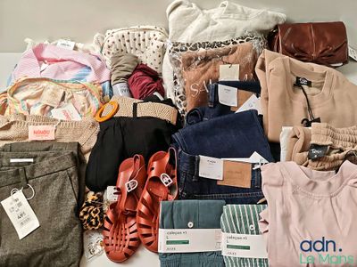 a pile of clothes and shoes on a bed