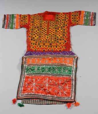 une robe brodée orange et verte accrochée à un mur
