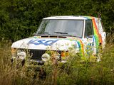 a van that is parked in the grass with a rainbow painted on it