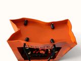 an orange bag that is sitting on a white surface