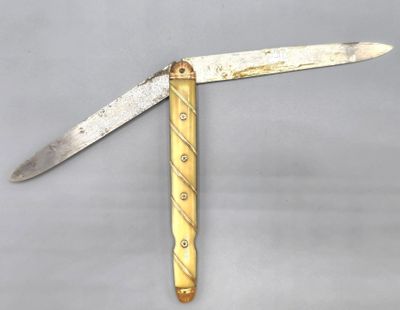un couteau au manche doré posé sur une surface grise