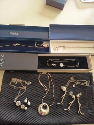 des colliers, des bracelets et des boucles d'oreilles en argent, rangés dans une boîte posée sur une table