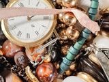 a pile of assorted jewelry with a gold watch on it