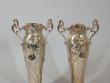 two silver vases sitting next to each other on a table