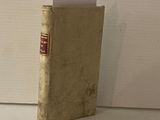 un petit livre sur lequel figure un nom, posé sur une table