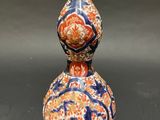 an orange and blue vase sitting on top of a black table