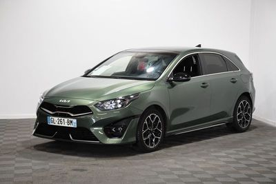 La voiture verte est garée dans une pièce au sol à carreaux.