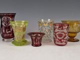 plusieurs vases en verre de différentes couleurs sont alignés sur une surface blanche
