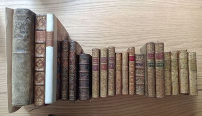 many old books lined up on a shelf on a table