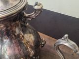 a silver tea pot sitting on a table next to a silver pitcher