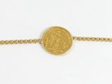 a close up of a gold coin on a chain on a white surface