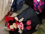 a pile of clothes and a stuffed animal on a bed