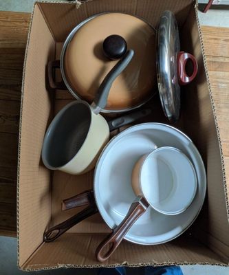 de nombreuses casseroles et poêles dans une boîte posée sur une table
