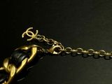 a black and gold bracelet with a gold anchor on it