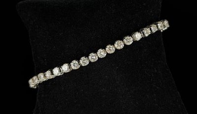a diamond tennis bracelet on a black mannequin