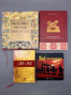 trois livres sont posés sur une surface grise, avec un ruban rouge