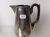 a silver pitcher sitting on a table next to a cup