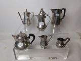 a lot of silver teapots and coffee pots on a clear shelf