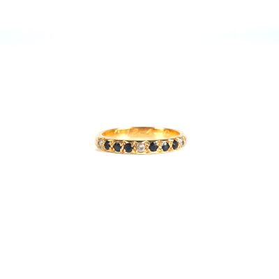 un gros plan d'une bague en or sertie de diamants noirs sur fond blanc