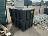 a pile of black containers sitting on the ground next to a fence