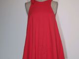 une robe rouge posée sur un mannequin contre un mur blanc