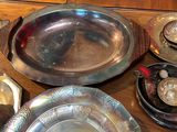 a lot of silver plates and bowls on the table
