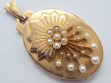 a gold locke with pearls on it on a white surface