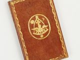 an old book with a gold emblem on it sitting on a white surface