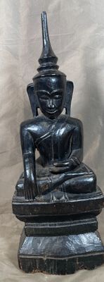 Bouddha assis en bois noirci dans le geste de prise à témoin…