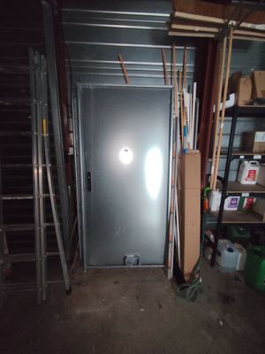 une porte métallique dans une pièce équipée d'étagères et d'une échelle