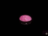 a pink candle that is lit up in the dark
