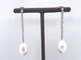a pair of pearl and diamond earrings on a stand