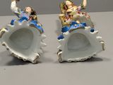 two figurines of people sitting on seashells