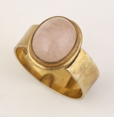 gros plan d'une bague en or avec une pierre rose
